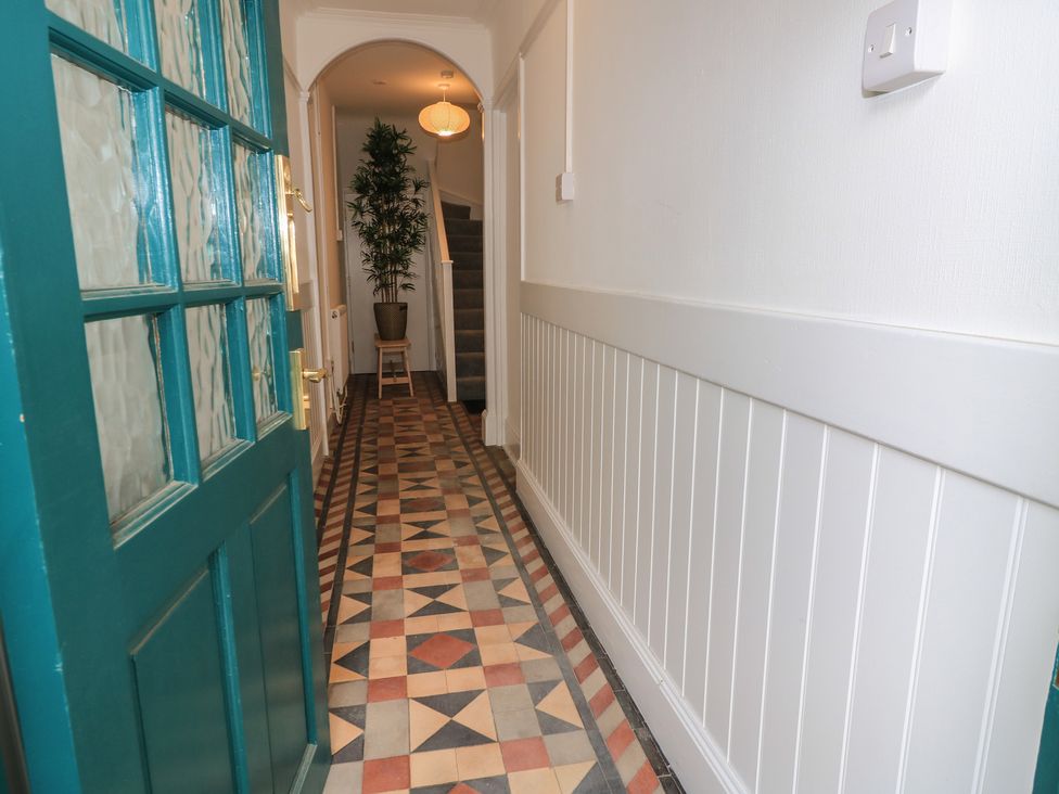 A hallway with an indoor plant and staircase at Still Waters in Swanage