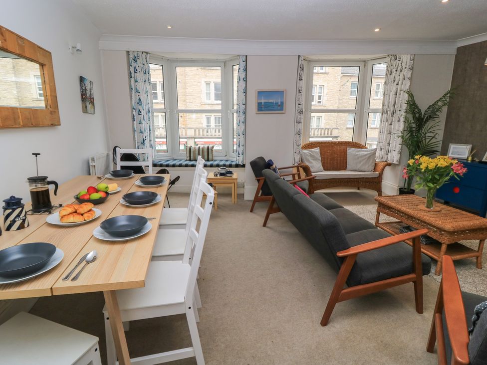 A living room featuring a dining table with chairs and a sofa at Still Waters in Swanage