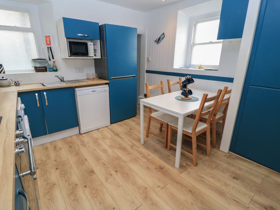 A kitchen with appliances and dining table at Still Waters in Swanage