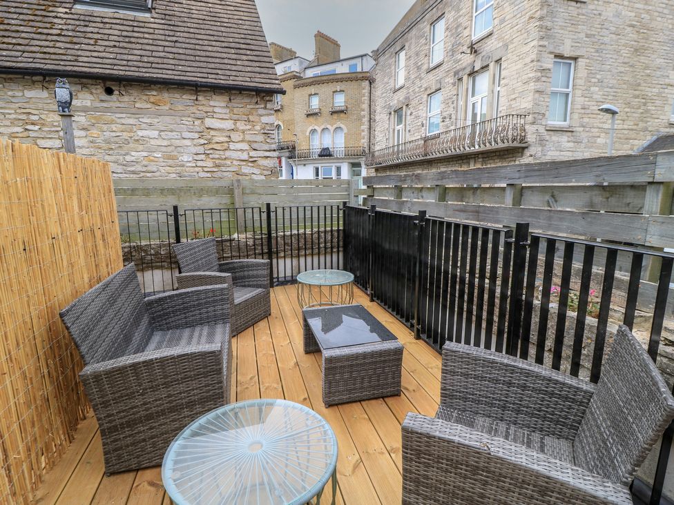 An outdoor patio with seating and a table at Still Waters in Swanage