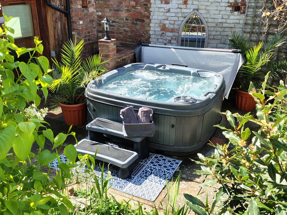 A hot tub with towels and plant pots in the garden at Runnymede in Tewkesbury