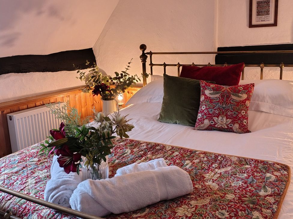 A bedroom with a bed and flowers on the bed at Runnymede in Tewkesbury