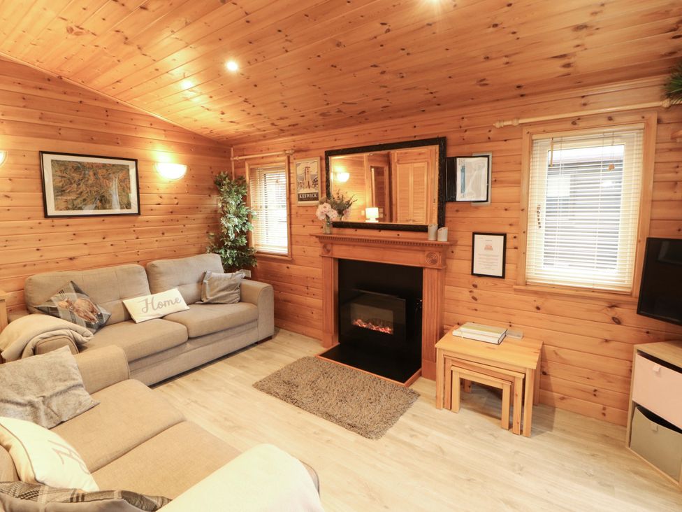 A living room with a sofa and a fireplace at The Fold, Number 28, Burnside Park near Keswick