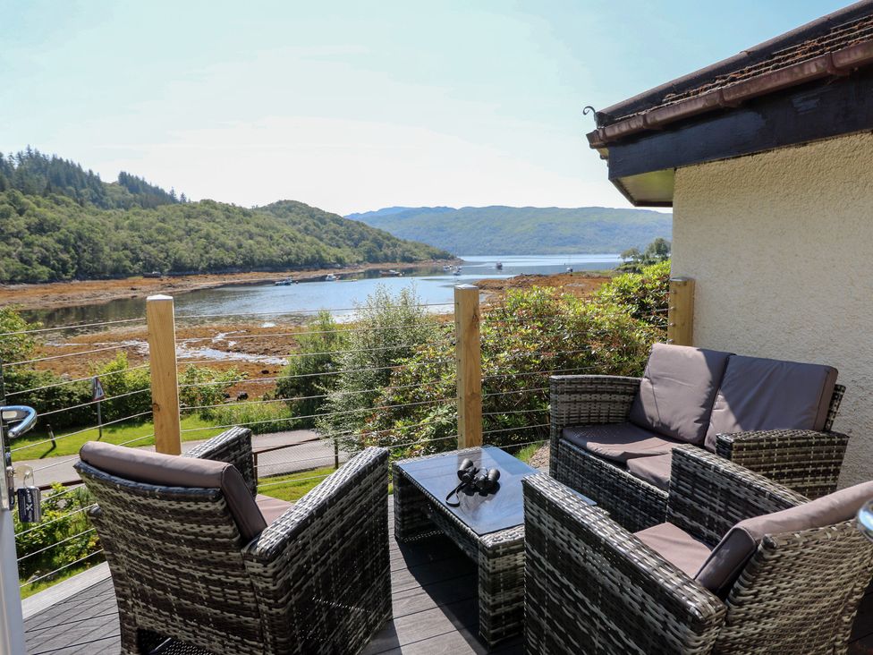 An outdoor seating area with chairs and a table overlooking a water view at Allt An Dorran in Salen
