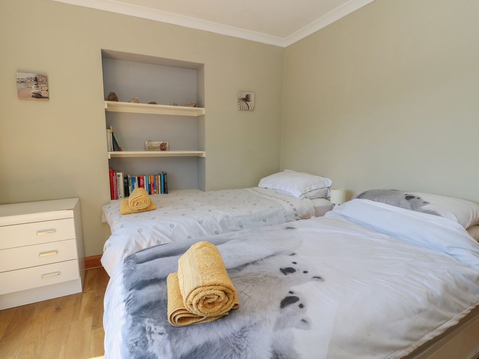 A bedroom with two beds and shelves containing books at Allt An Dorran in Salen