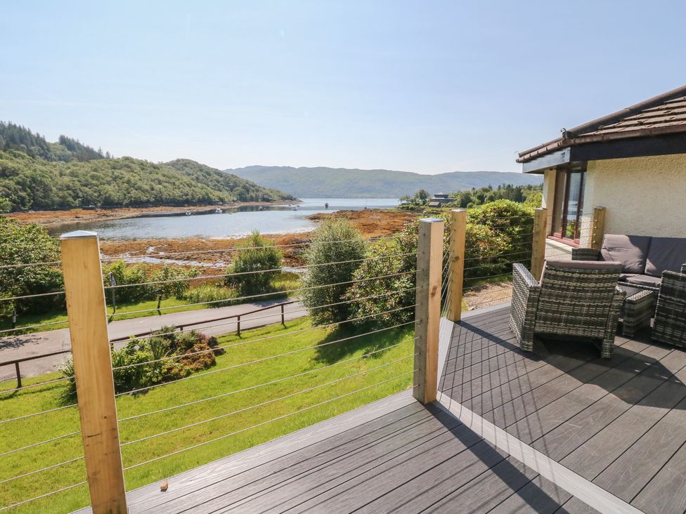 A deck with furniture overlooking water at Allt An Dorran in Salen