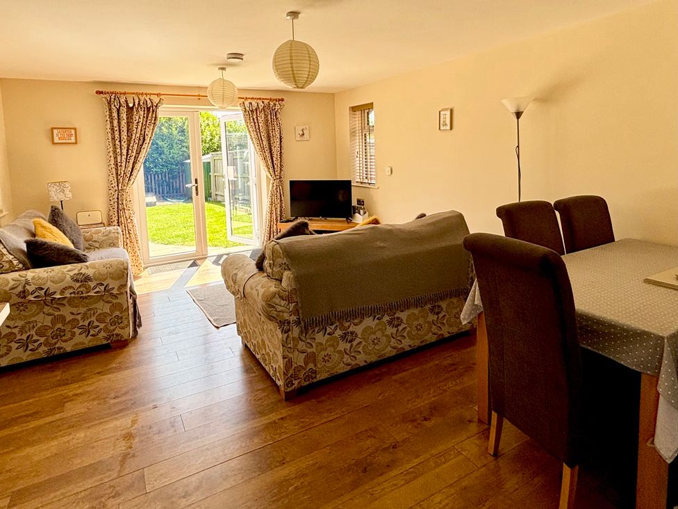 A living room with a sofa, table, and television at The Old Gate House Annexe in Alford