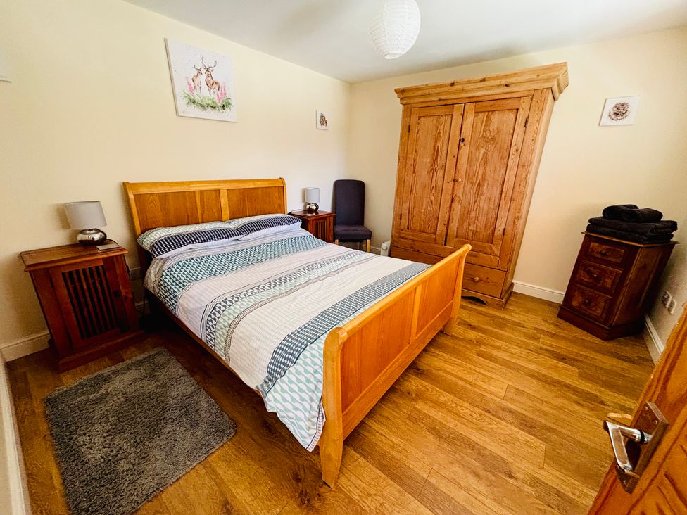 A bedroom with a bed and wooden furniture at The Old Gate House Annexe in Alford