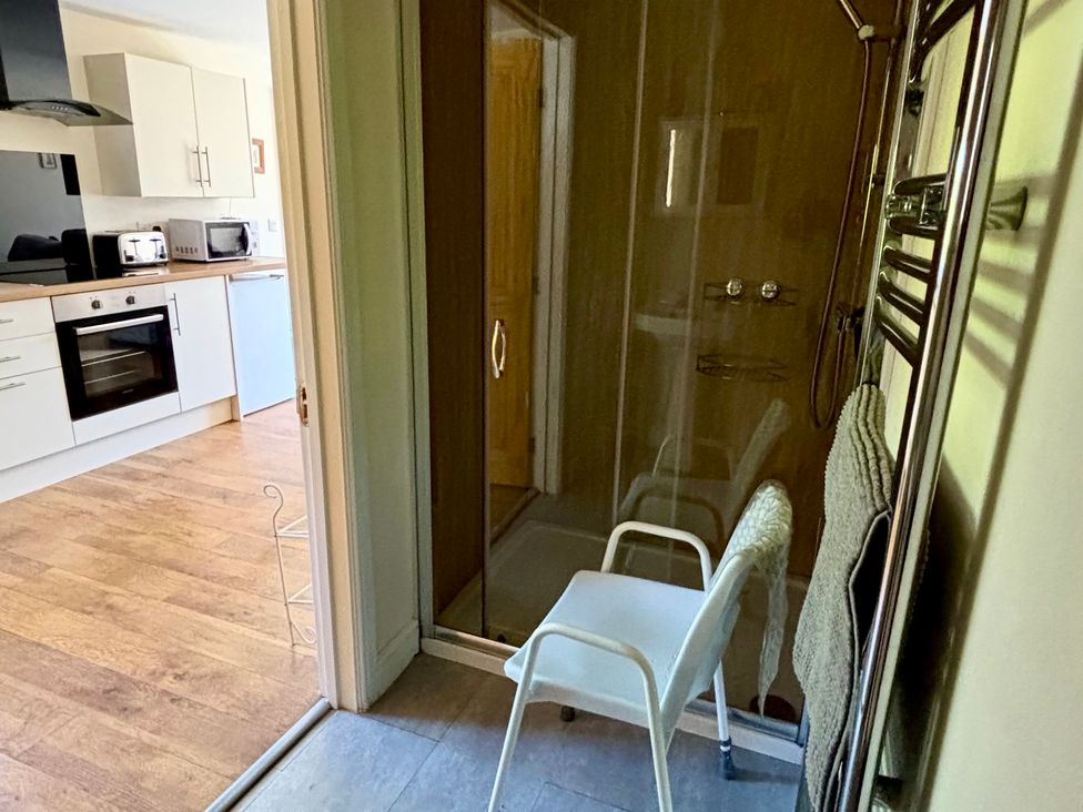 A bathroom with a shower and a chair at The Old Gate House Annexe in Alford