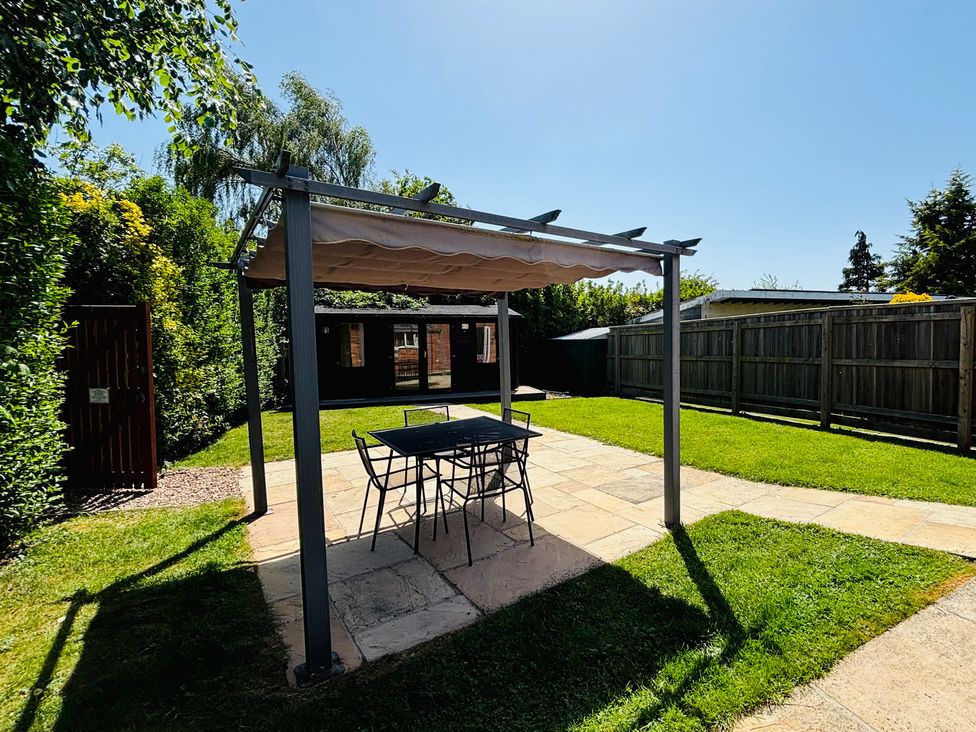 A garden with a pergola and table at The Old Gate House Annexe in Alford