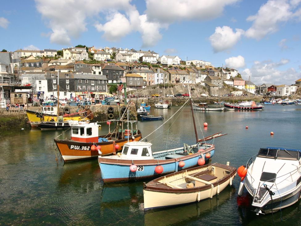 A harbor with various boats docked and houses on a hill in the background at Pirata in Charlestown near St Austell