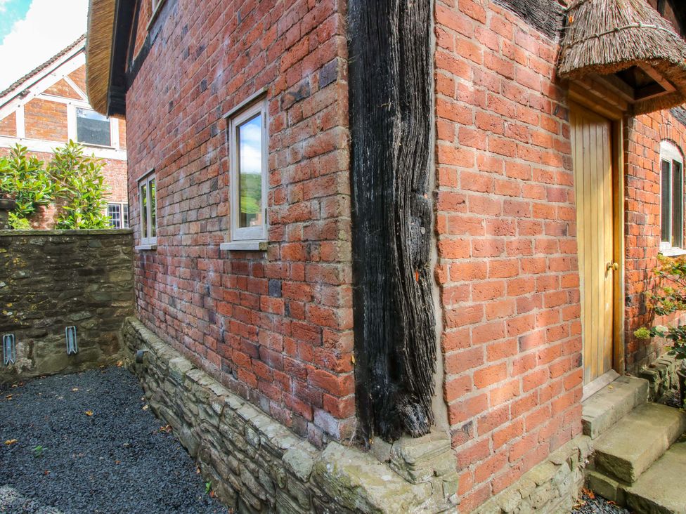 An exterior view of a brick building with stone walls and windows at Manor Cottage in Little Stretton near Church Stretton