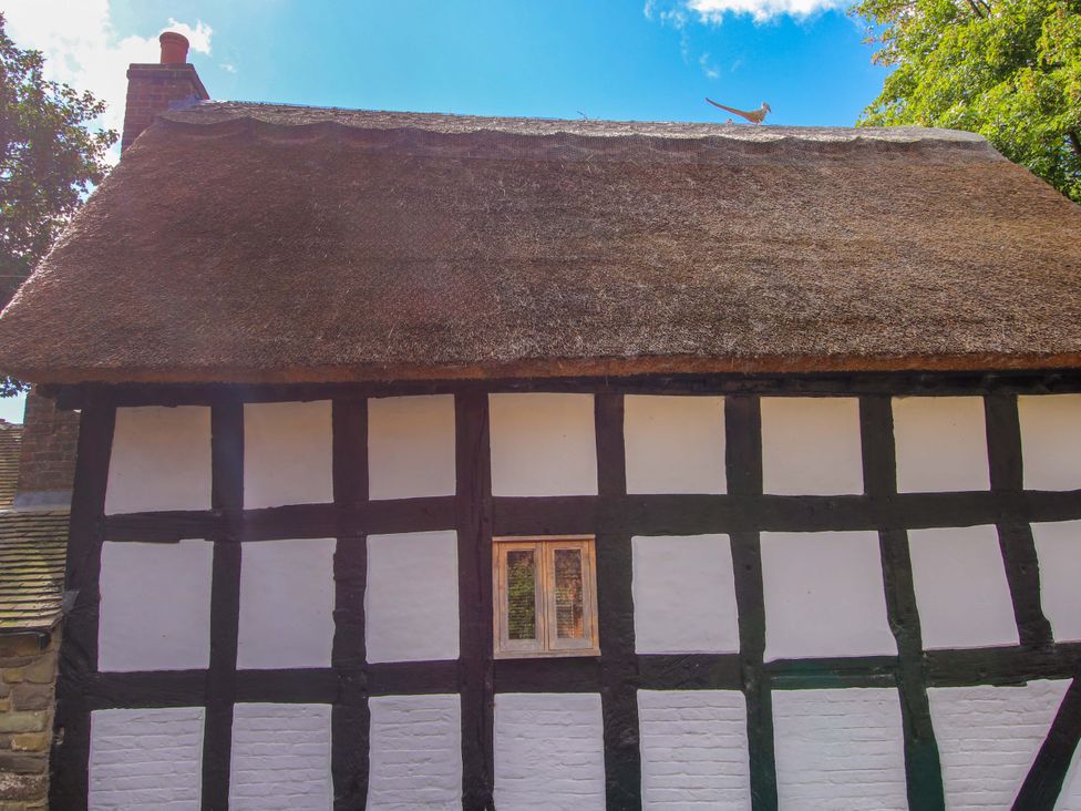 A thatched cottage with wooden beams and a small window at Manor Cottage in Little Stretton near Church Stretton