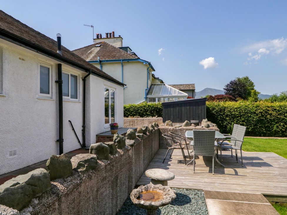 A garden with a table and chairs next to a house at Driftwood Cottage in Keswick