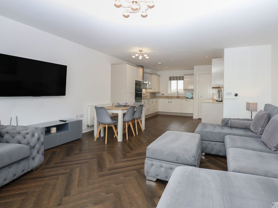 A living room with a sofa, television, and dining table at 26 Awel Y Mor Pwllheli