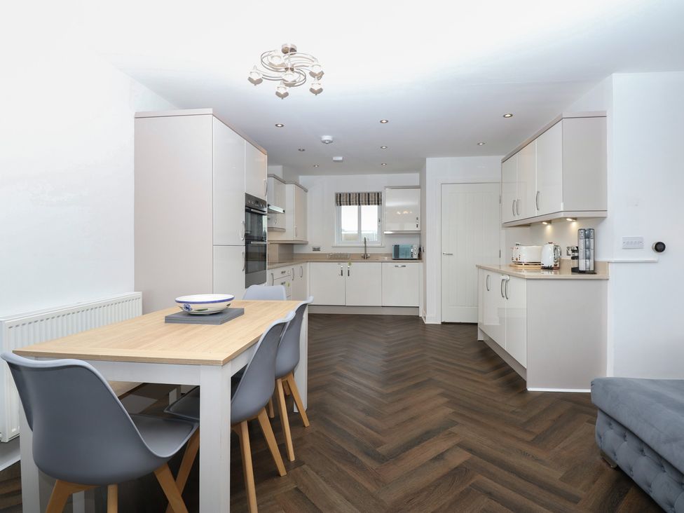 A kitchen with a dining table and chairs at 26 Awel Y Mor Pwllheli