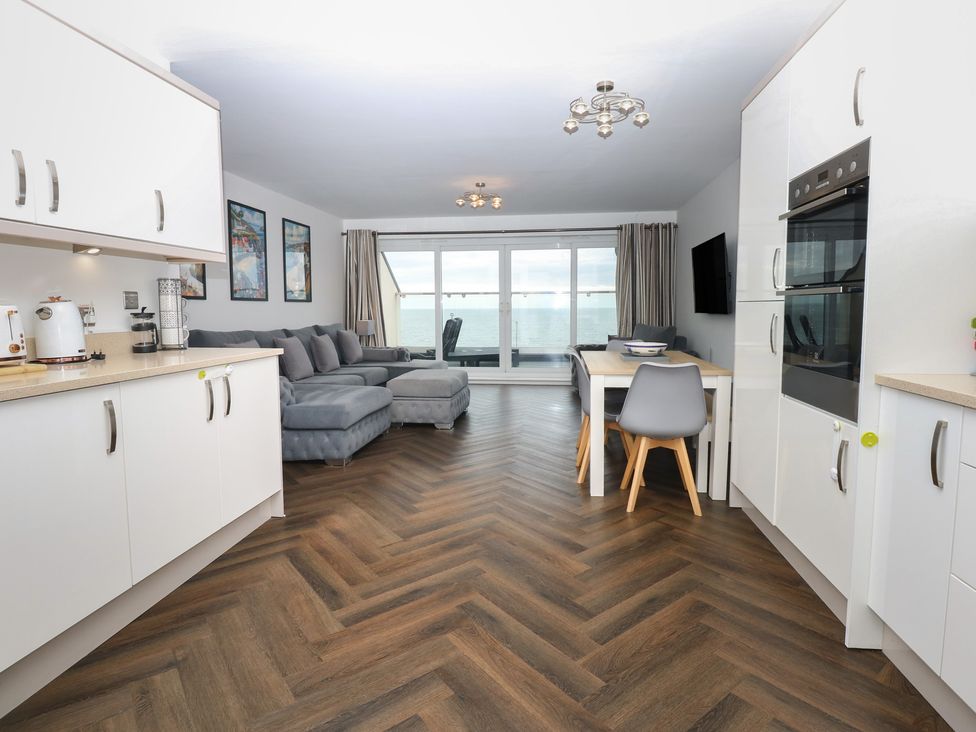 A living room with a sofa and dining table at 26 Awel Y Mor in Pwllheli