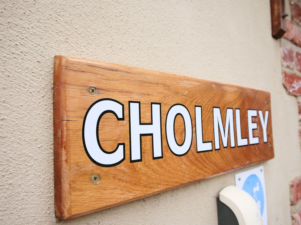 A wooden sign with the text CHOLMLEY attached to a wall at Chomley @ Summerfield Farm in Hawsker