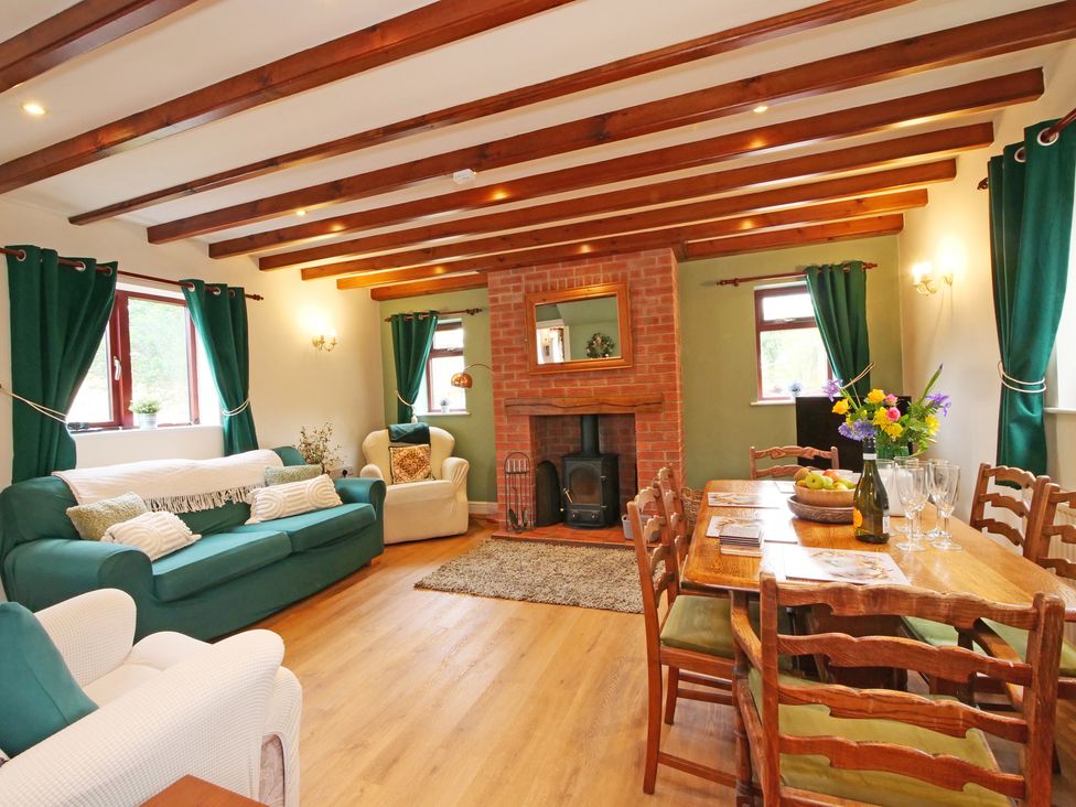 A living room with a fireplace and dining table at Chomley @ Summerfield Farm in Hawsker