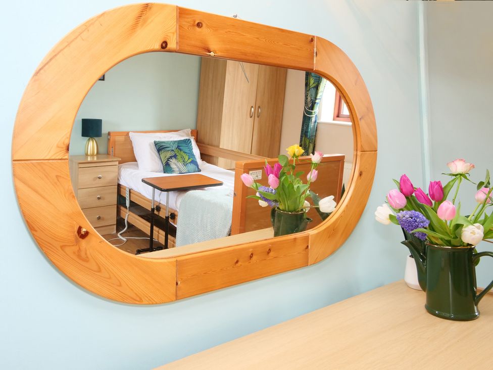 A bedroom with a bed, lamp, and flower vase at Chomley @ Summerfield Farm in Hawsker