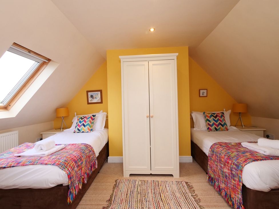 A bedroom with two beds and a wardrobe at Chomley @ Summerfield Farm in Hawsker