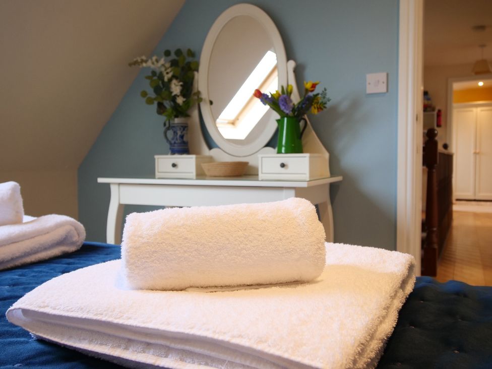 A bedroom with towels on a bed and a dresser with flowers at Chomley @ Summerfield Farm Hawsker