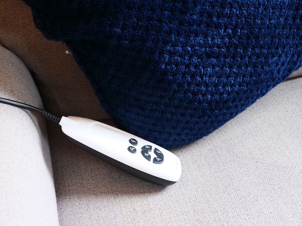 A remote control next to a blue cushion on a couch at Albany @ Summerfield Farm, Hawsker