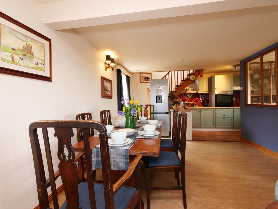 A dining room with table and chairs leading to a kitchen at Albany @ Summerfield Farm Hawsker