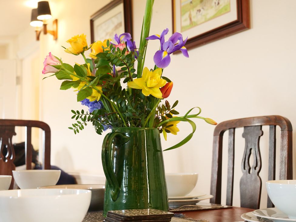 A dining room with flowers in a vase and table settings at Albany @ Summerfield Farm in Hawsker