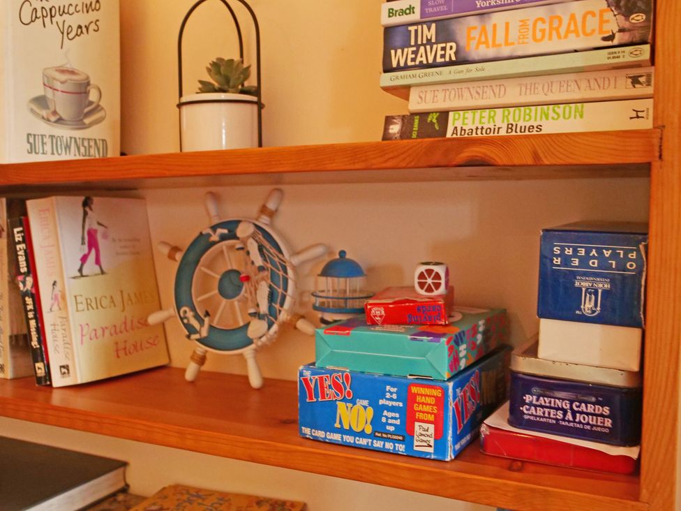 A shelf with books, a plant, and board games at Albany @ Summerfield Farm, Hawsker