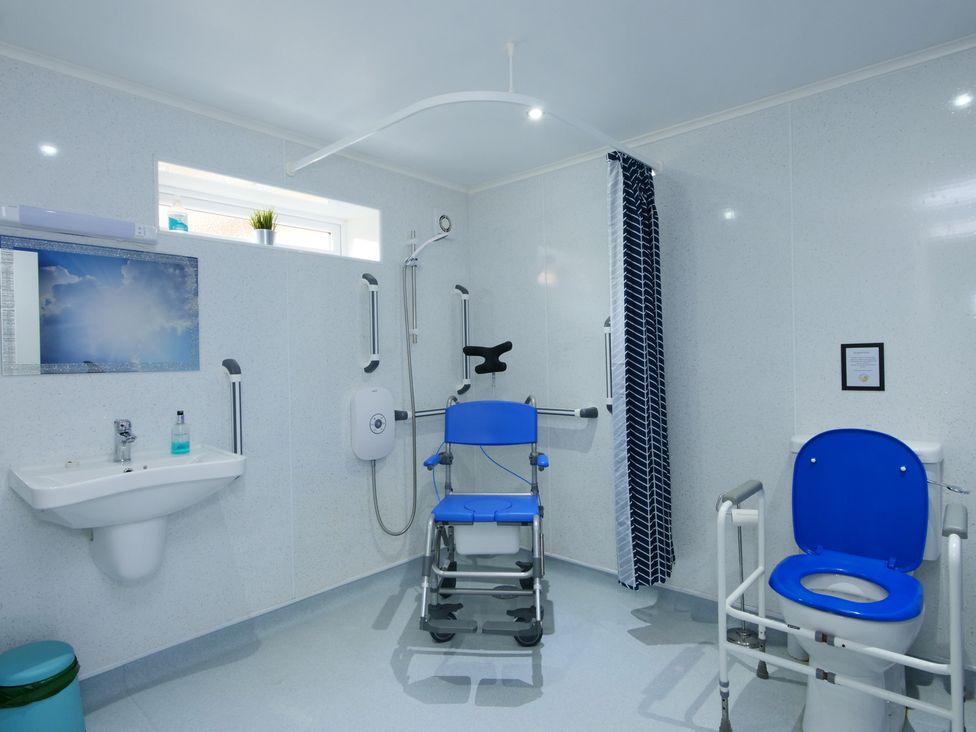 A bathroom with a shower chair and raised toilet seat at Albany @ Summerfield Farm in Hawsker