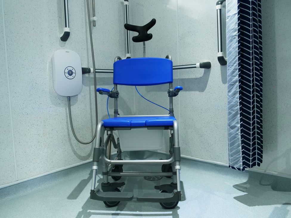 A bathroom with a shower chair and shower controls at Albany @ Summerfield Farm, Hawsker