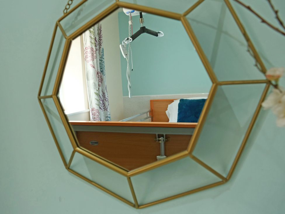 A mirror reflecting a hospital bed with a curtain in a bedroom at Albany @ Summerfield Farm Hawsker