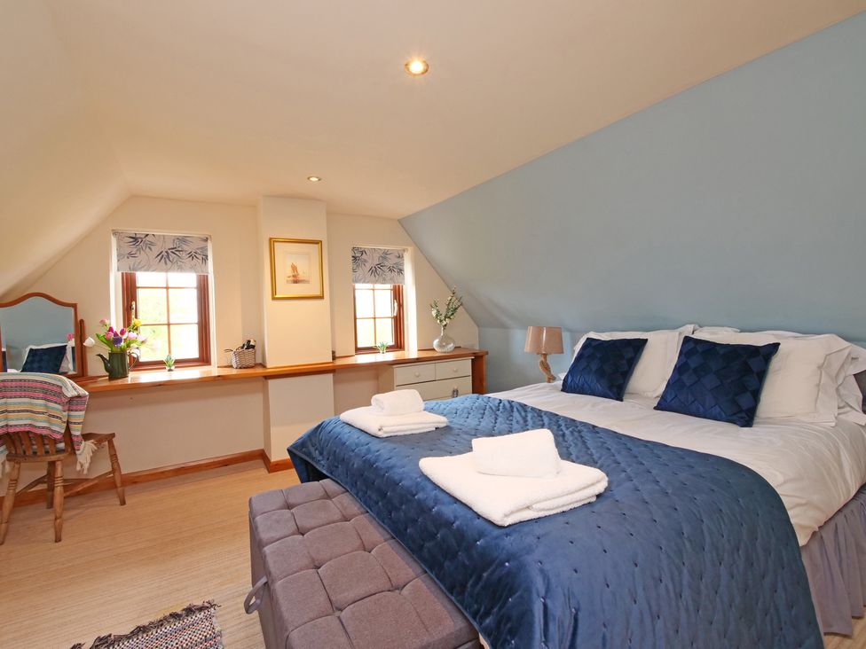 A bedroom with a bed, mirror, and windows at Albany @ Summerfield Farm, Hawsker