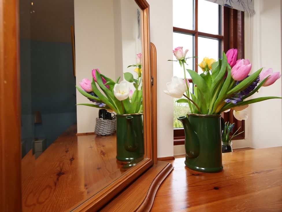 A table with flowers in a vase and a mirror at Albany @ Summerfield Farm, Hawsker