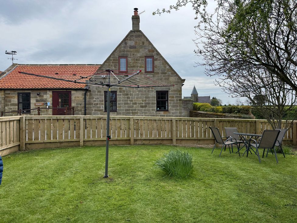 A garden with a table and chairs in front of a house at Albany @ Summerfield Farm, Hawsker