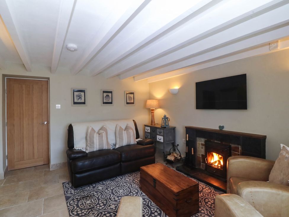 A living room with a sofa, fireplace, and television at 4 Bryn Llan, Aberdaron