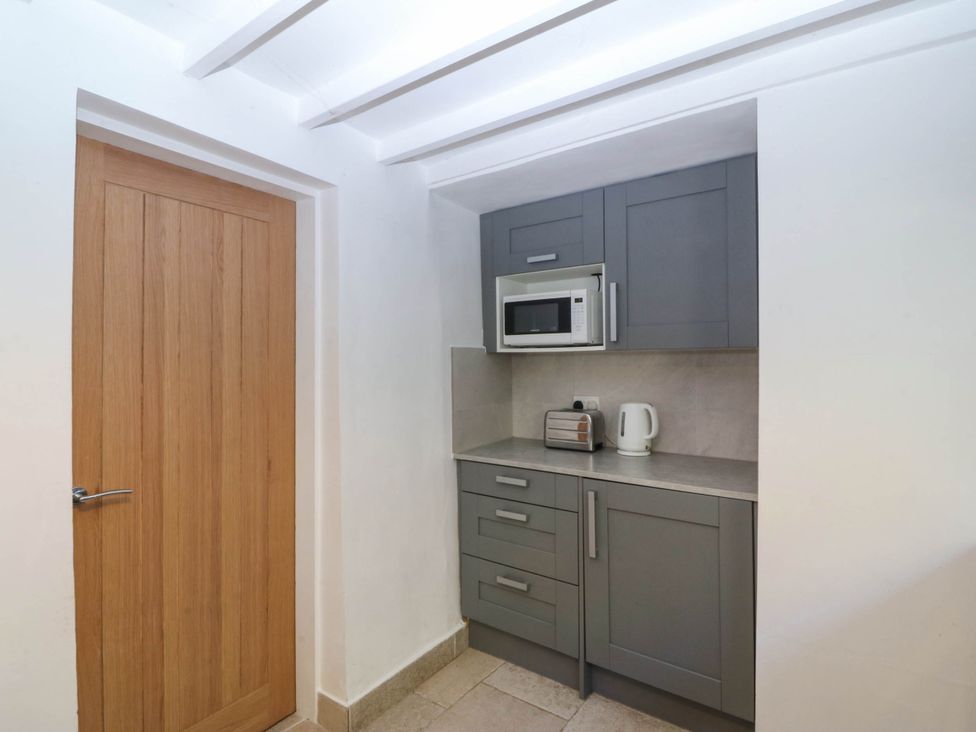 A kitchen with a microwave, toaster, and kettle at 4 Bryn Llan, Aberdaron