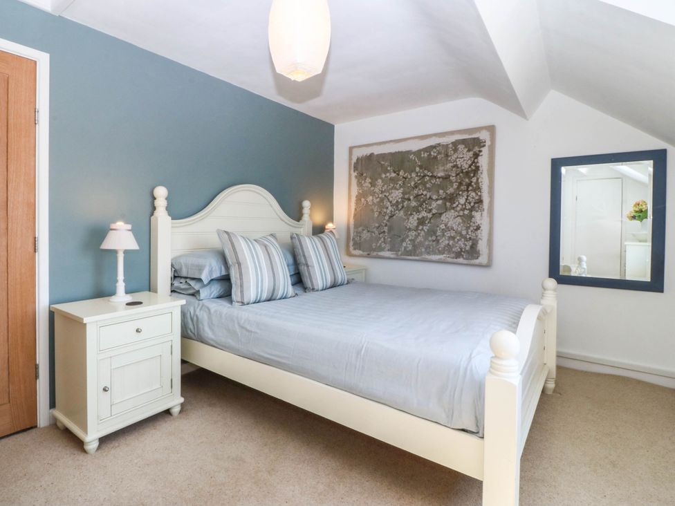 A bedroom featuring a bed, nightstand, and mirror at 4 Bryn Llan, Aberdaron