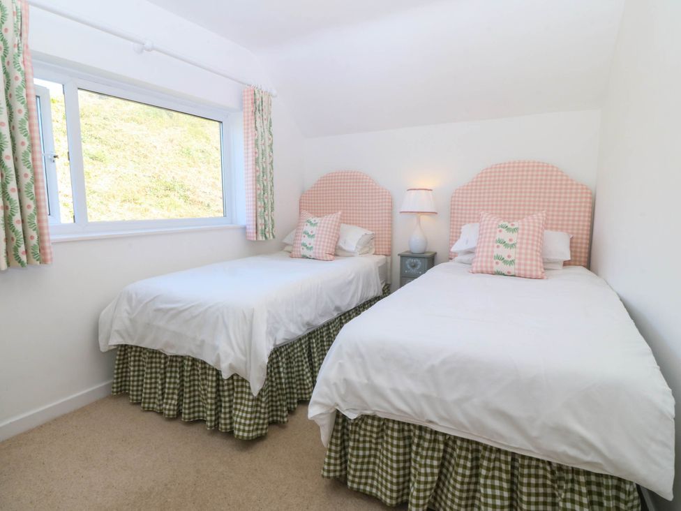 A bedroom with two beds and a window at 4 Bryn Llan Aberdaron