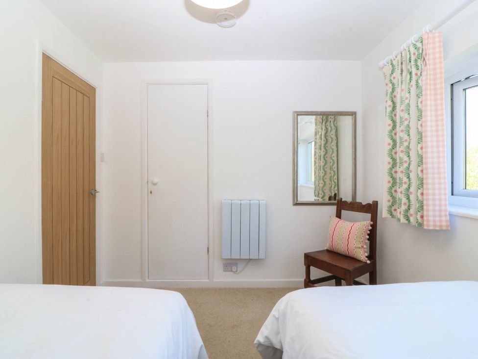 A bedroom with a bed, chair, and mirror at 4 Bryn Llan in Aberdaron