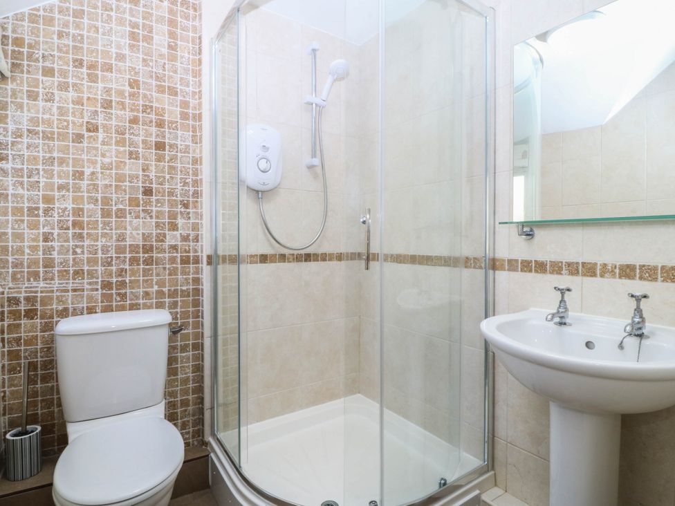 A bathroom with a shower, toilet, and sink at 4 Bryn Llan in Aberdaron