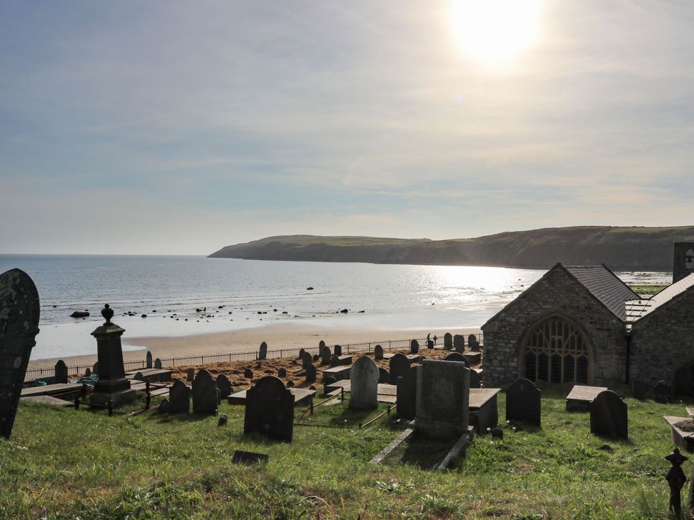 A beach view with gravestones and a church at 5 Bryn Llan Pwllheli