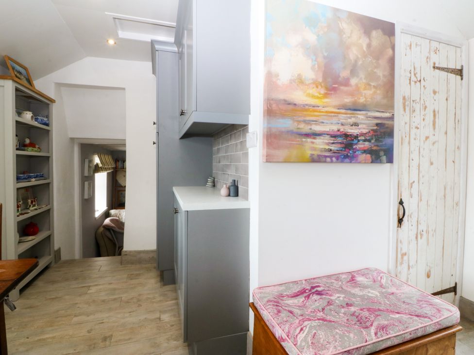 A hallway with cabinets, shelves, and a painting at 5 Bryn Llan in Pwllheli