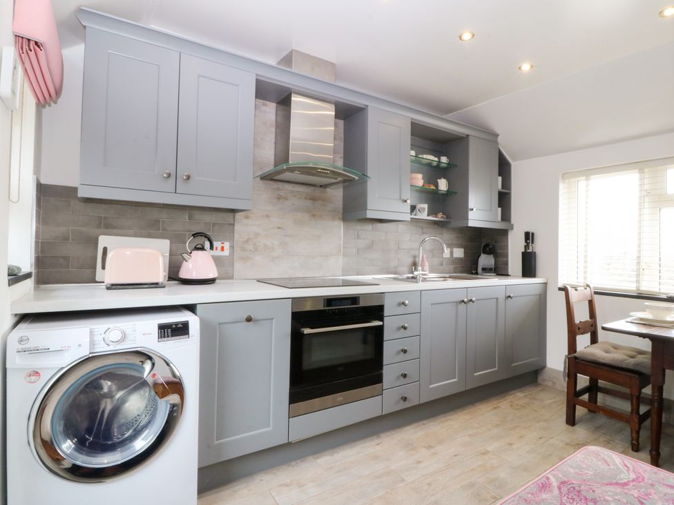 A kitchen with appliances and furniture at 5 Bryn Llan in Pwllheli