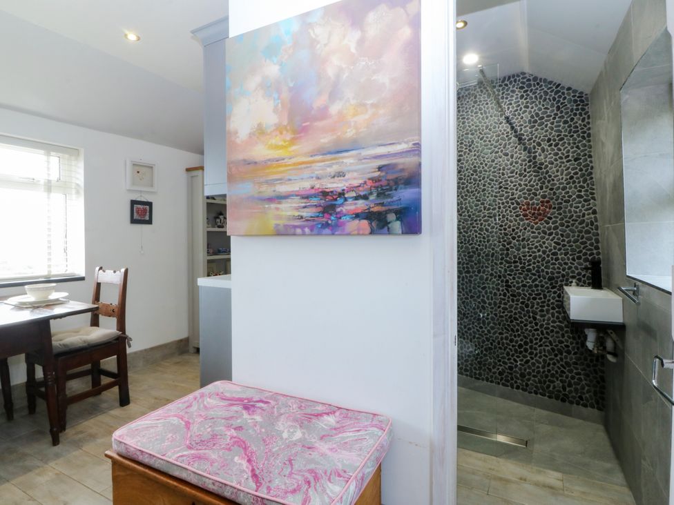 A dining area with a table and chair near a bathroom at 5 Bryn Llan Pwllheli