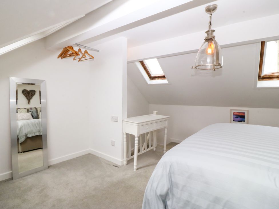 A bedroom with a bed, desk, and mirror at 5 Bryn Llan Pwllheli