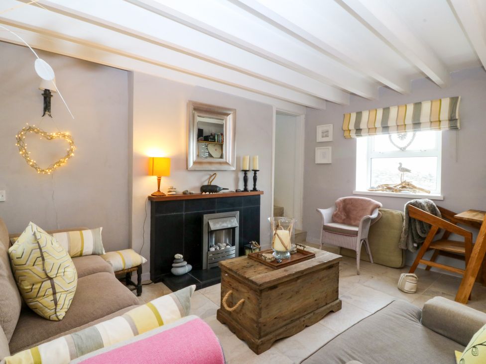 A living room with a wooden coffee table and chairs at 5 Bryn Llan in Pwllheli
