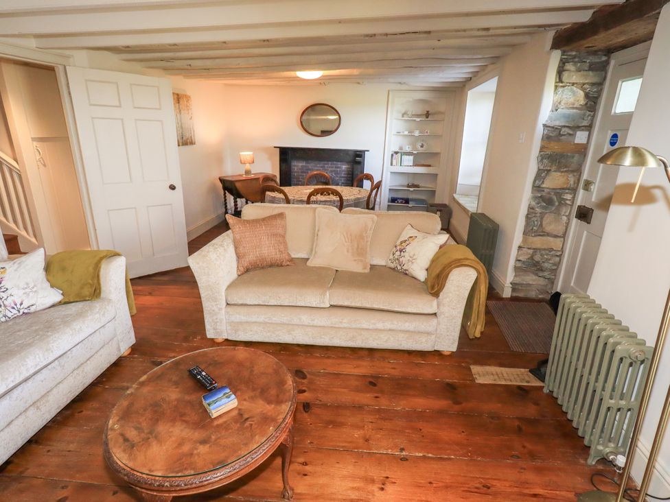 A living room with a sofa, coffee table, and fireplace at Bridge End Cottage Haverthwaite near Cartmel