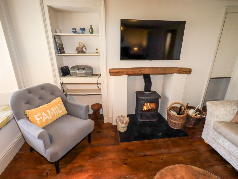 A living room with a television and a fireplace at Bridge End Cottage in Haverthwaite near Cartmel